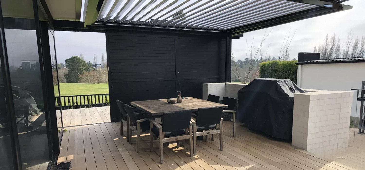 Residential deck with motorised louvred roof over dining area, showing how louvred roofs create shade, shelter and flexible outdoor living space in changing weather conditions.