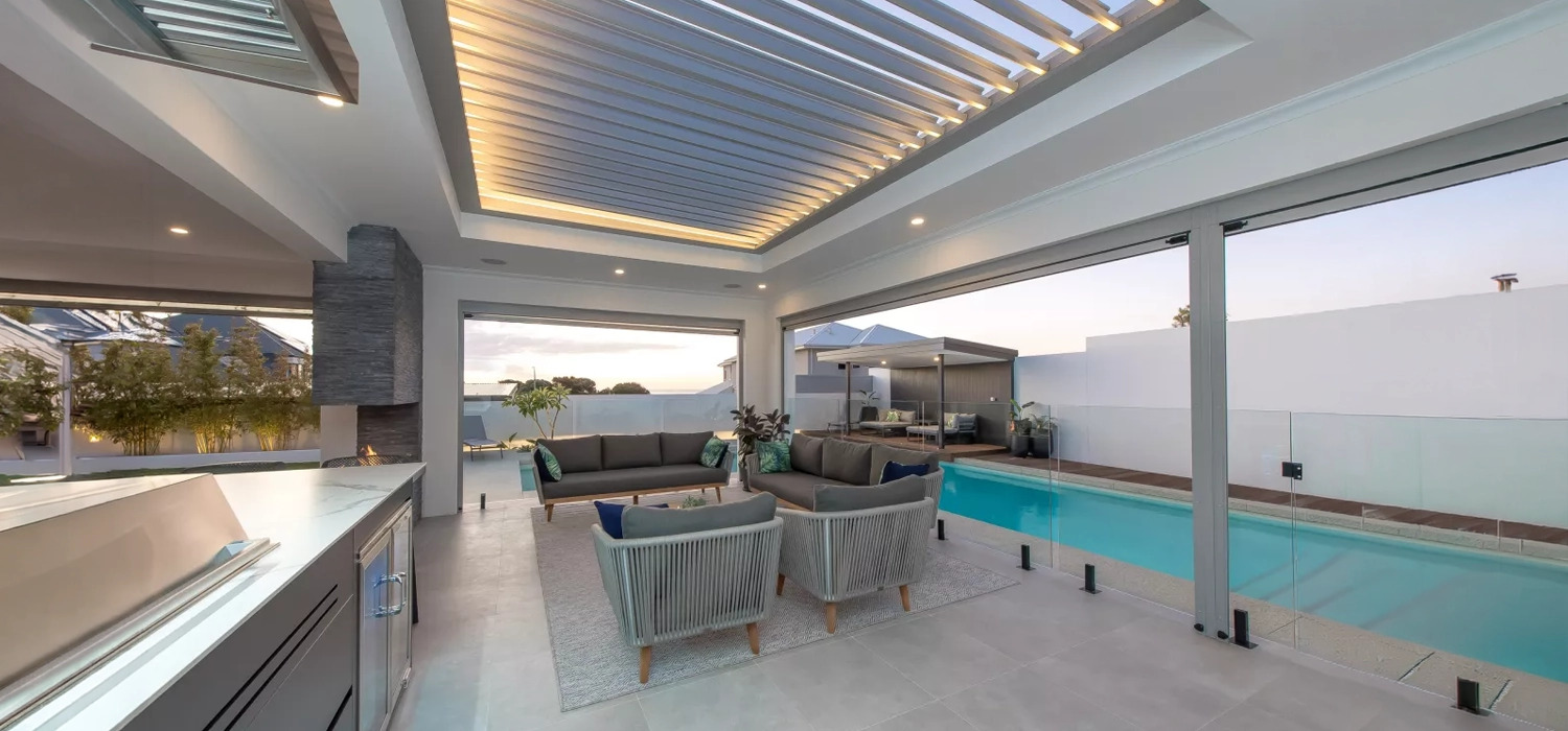 Contemporary patio with motorised louvred roof, seating area and pool, highlighting the benefits of louvred roofs for shade, ventilation and year round outdoor comfort.