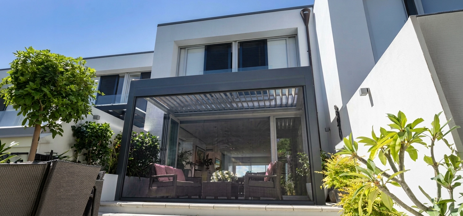 A modern home featuring a patio area with outdoor blinds for shade and privacy.