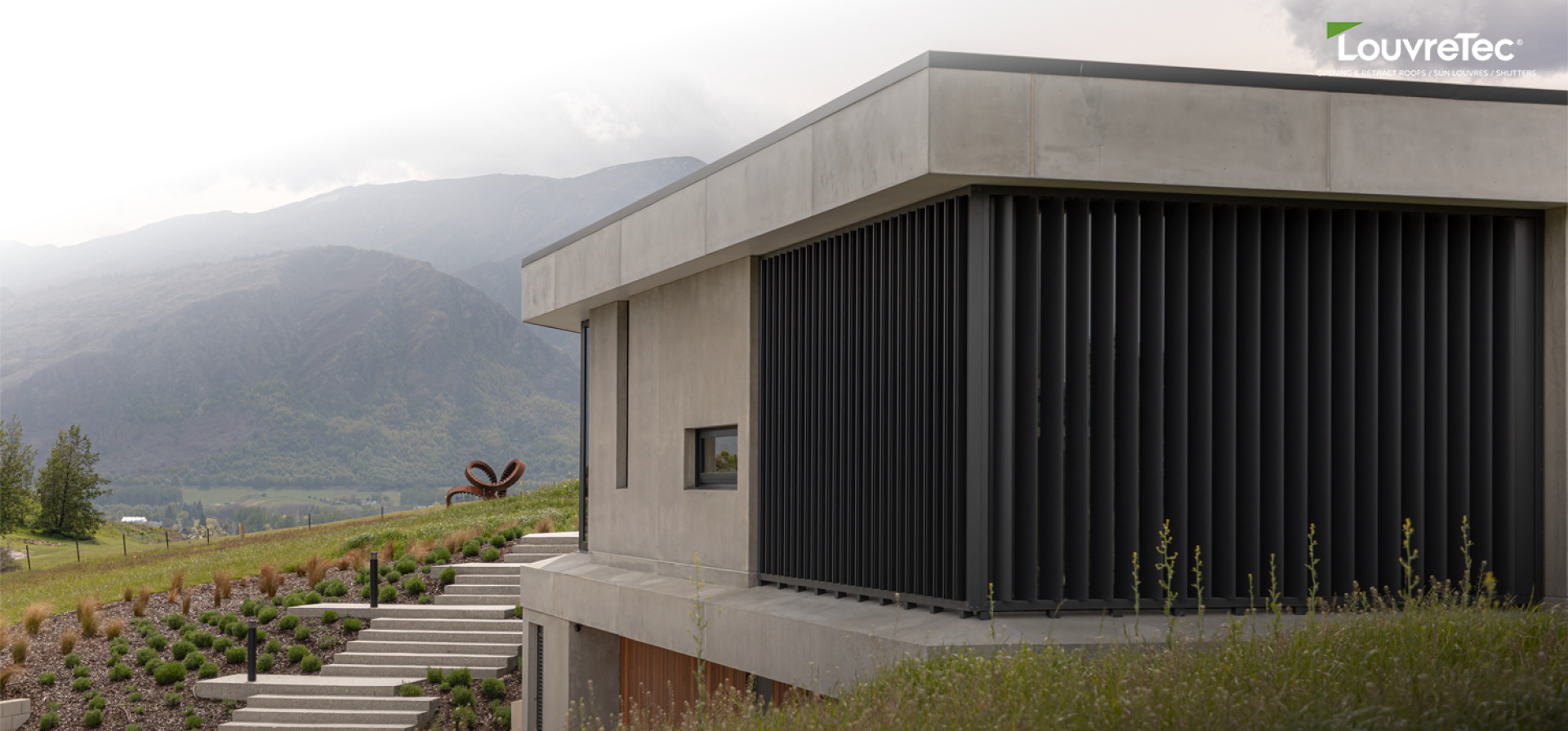 Modern concrete home with vertical sun louvre screens from the Sun Louvre Collections, providing privacy and shading with a mountain backdrop