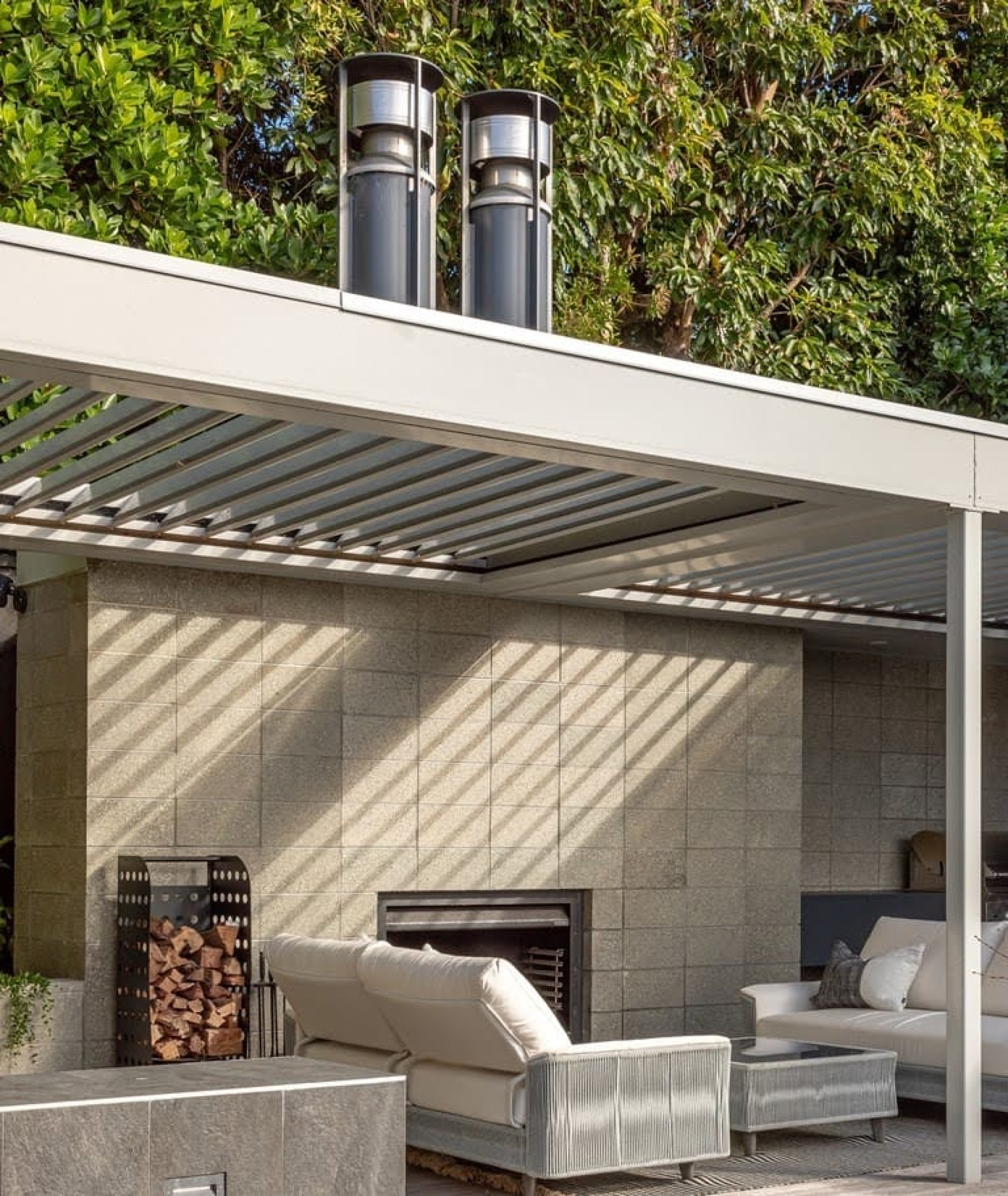 Modern outdoor living area with an adjustable Louvretec louvre roof, outdoor lounge furniture, and a tiled feature wall