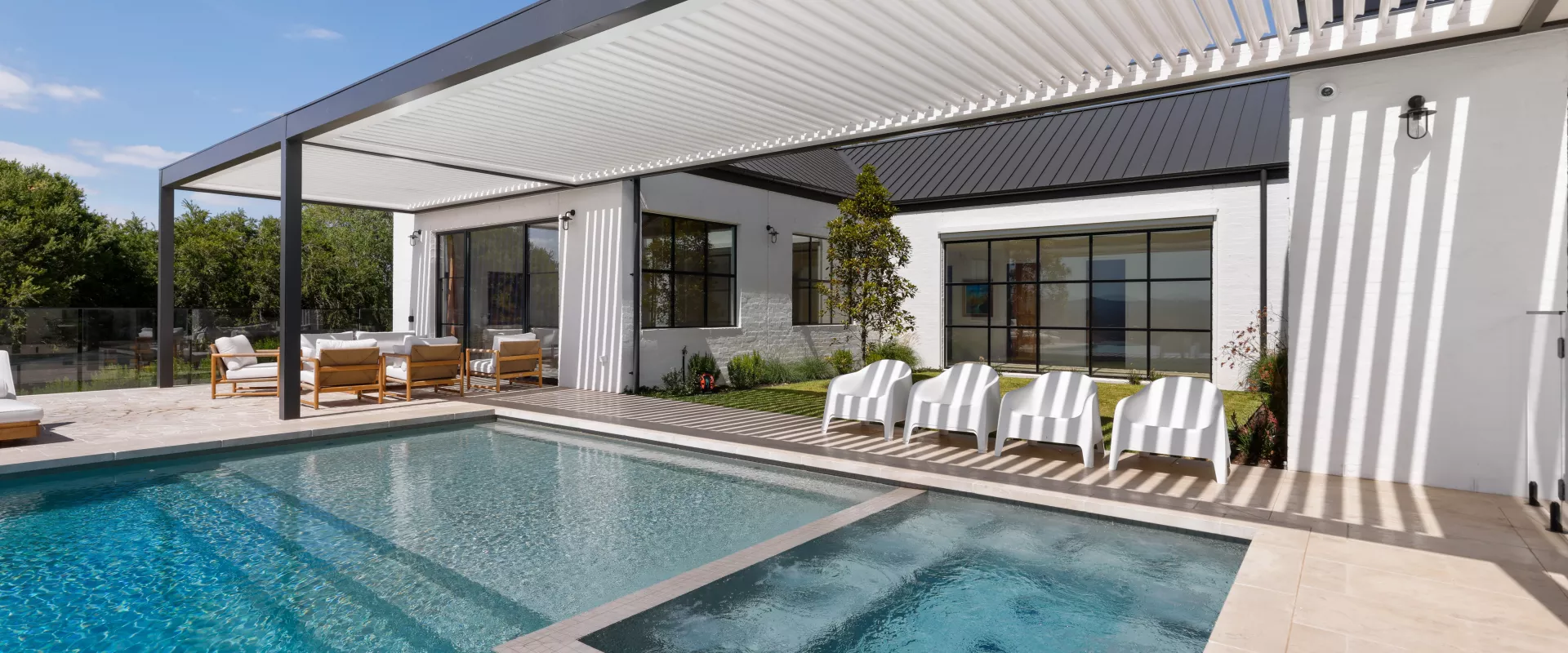 Luxury outdoor space featuring a modern home, sparkling pool, and adjustable louvered pergola for comfort.