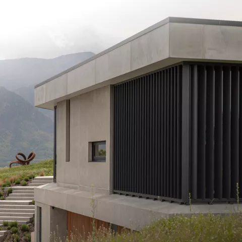 Modern concrete home with vertical sun louvre screens from the Sun Louvre Collections, providing privacy and shading with a mountain backdrop