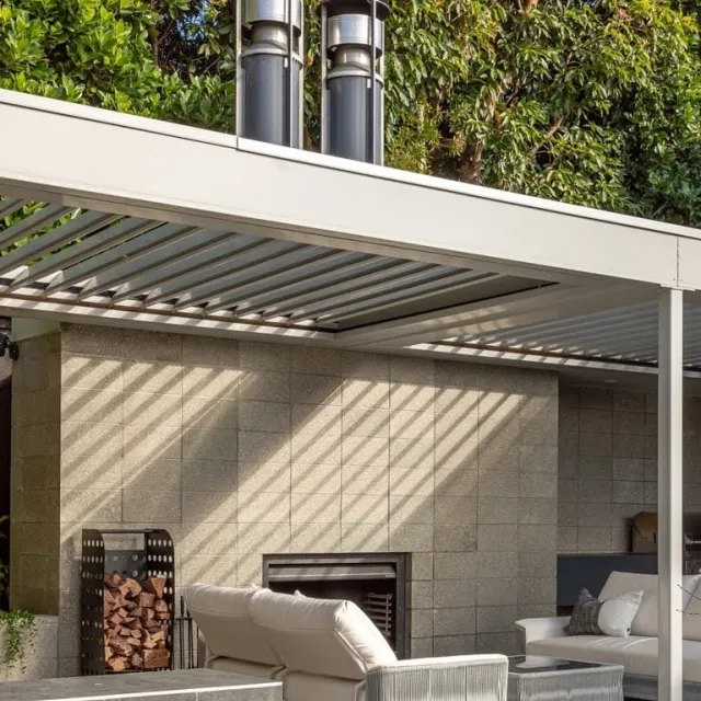 Modern outdoor living area with an adjustable Louvretec louvre roof, outdoor lounge furniture, and a tiled feature wall