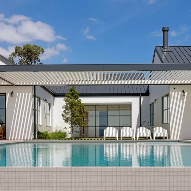 Contemporary home outdoor area with pool and patio, featuring a Louvretec opening louvre roof that provides adjustable shade and airflow.